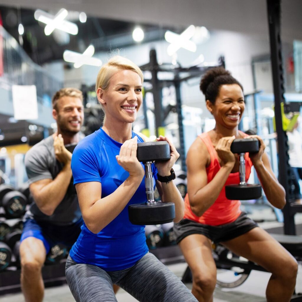 A group of men and women lifting weights together in a gym class session