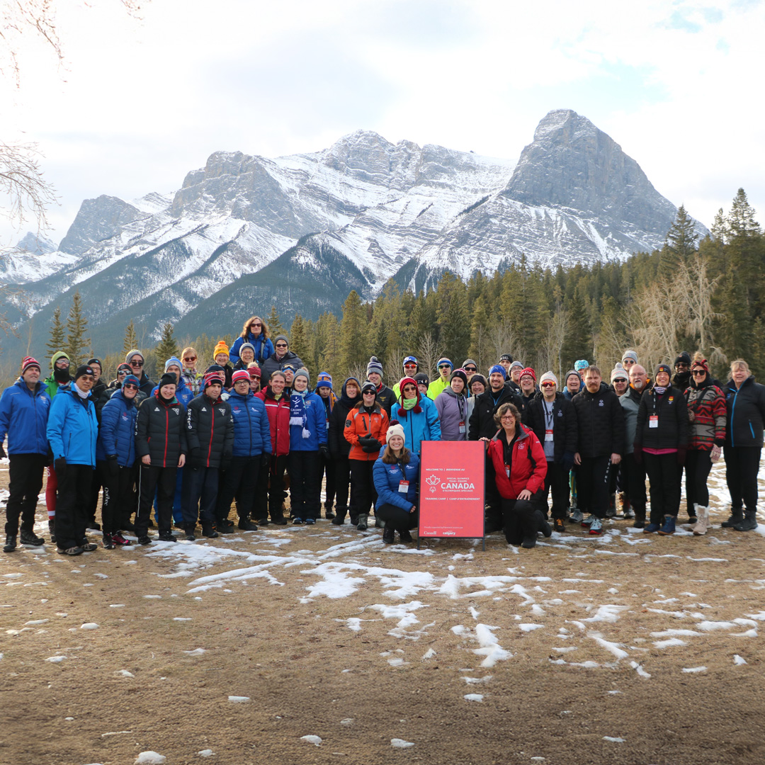 Team Canada of Special Olympics seen in front of high mountains and tall trees during winter