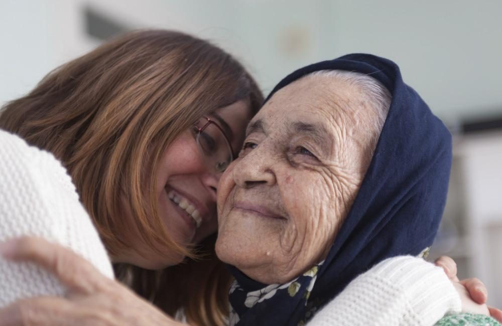 Two people embrace and hug; one of them is a senior.