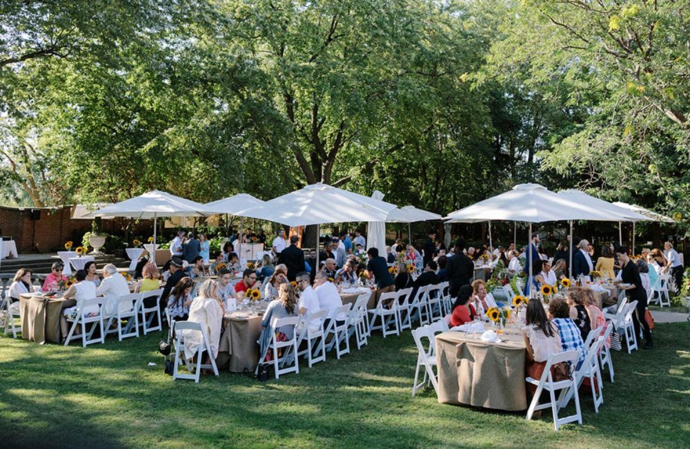 A group of people gather outside for Cena in Famiglia in the Villa Colombo gardens.