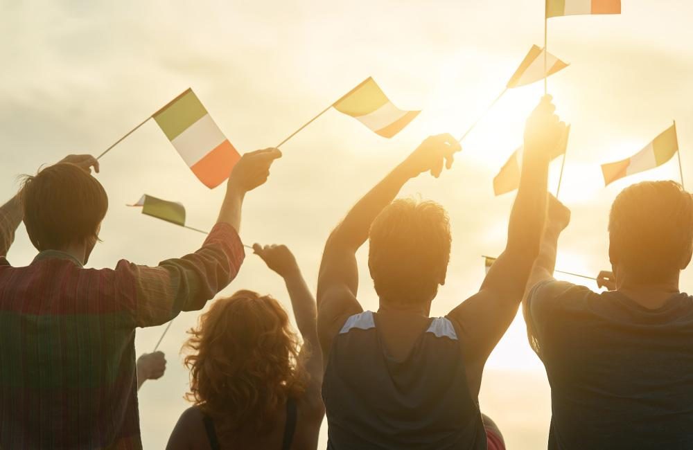 A group of people celebrating and waving Italian flags outside.